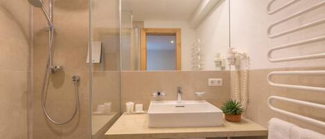 A modern bathroom with a glass shower enclosure, a white sink, and a towel rack.