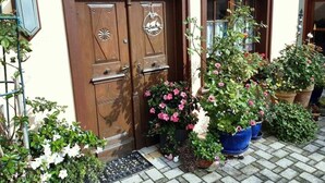 Ein traditionelles Gebäude mit zwei Holztüren, einem kleinen Fenster und einer Vielzahl von Blumentöpfen und Blumen davor.