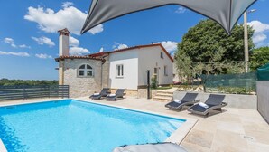 A swimming pool with lounge chairs, a stone building with a red roof, and a clear blue sky. - Modern Villa Aria with beautiful garden and private Pool near Vrsar (Vrsar)