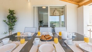 A breakfast table set with plates, cups, and glasses of orange juice, with a view of the outdoors through a large window. - Modern Villa Aria with beautiful garden and private Pool near Vrsar (Vrsar)