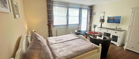 A bedroom with a bed, bedside table, lamp, and a TV on a dresser.