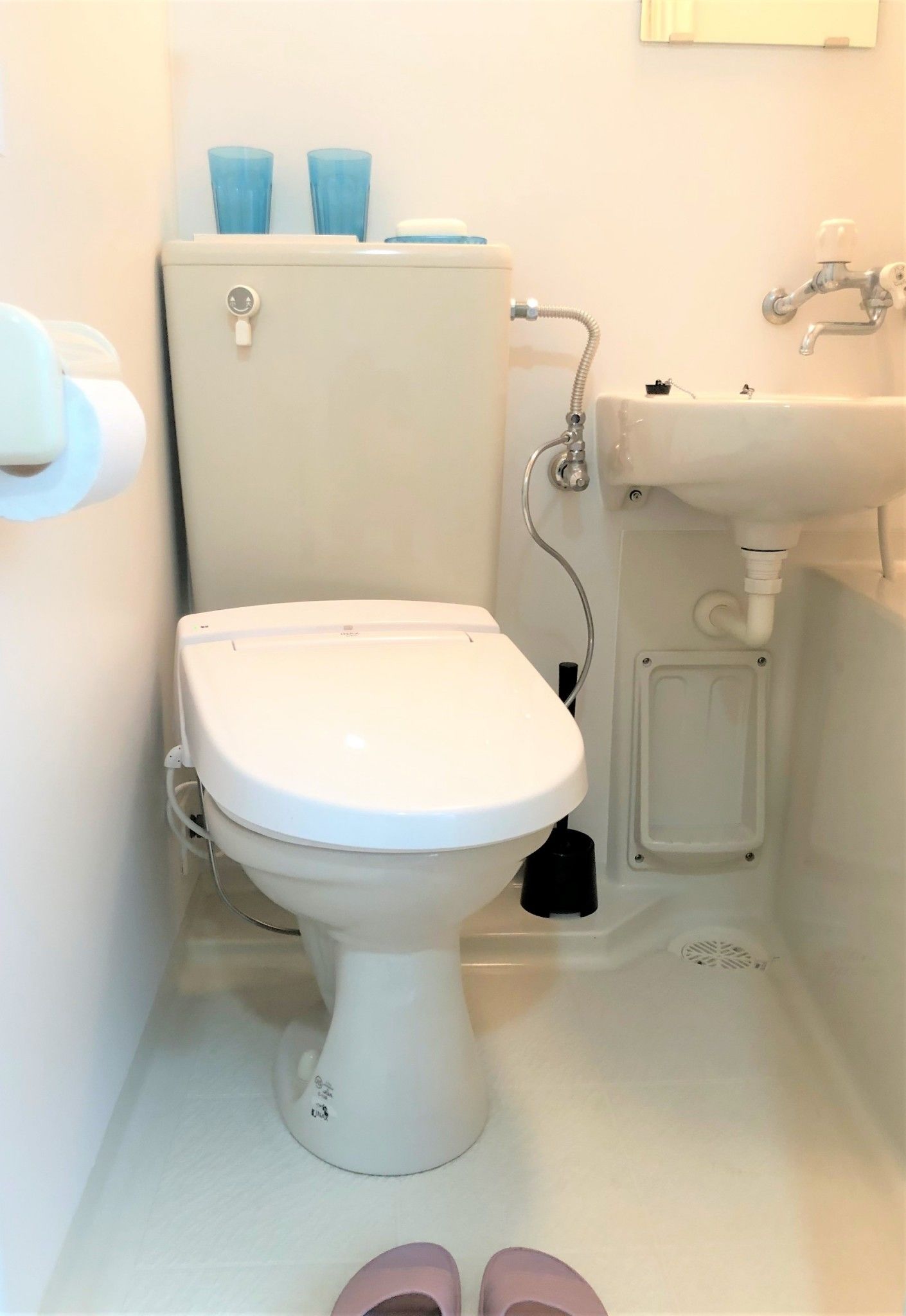 Un baño pequeño con inodoro, lavamanos y dispensador de papel higiénico.