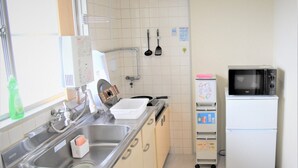 A compact kitchen with a sink, stove, microwave, and a small refrigerator. - U-shuku Ar5 (Osaka)