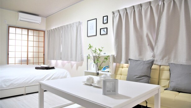 A hotel room with a bed, a sofa, a table, and a window with curtains. - U-shuku Ar5 (Osaka)