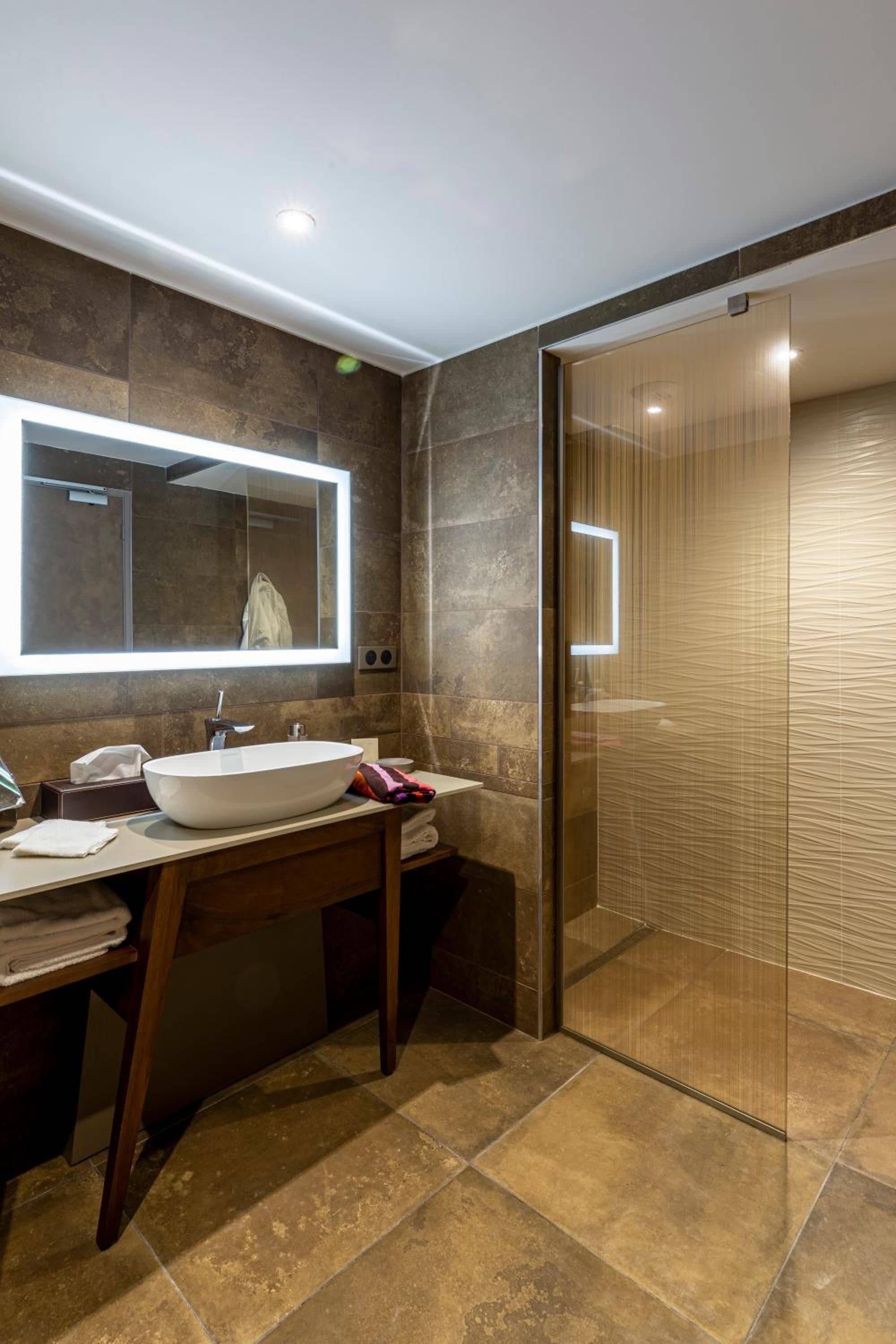 A modern bathroom with a large mirror, a white sink, and a glass shower enclosure.