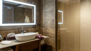 A modern bathroom with a large mirror, a white sink, and a glass shower enclosure.