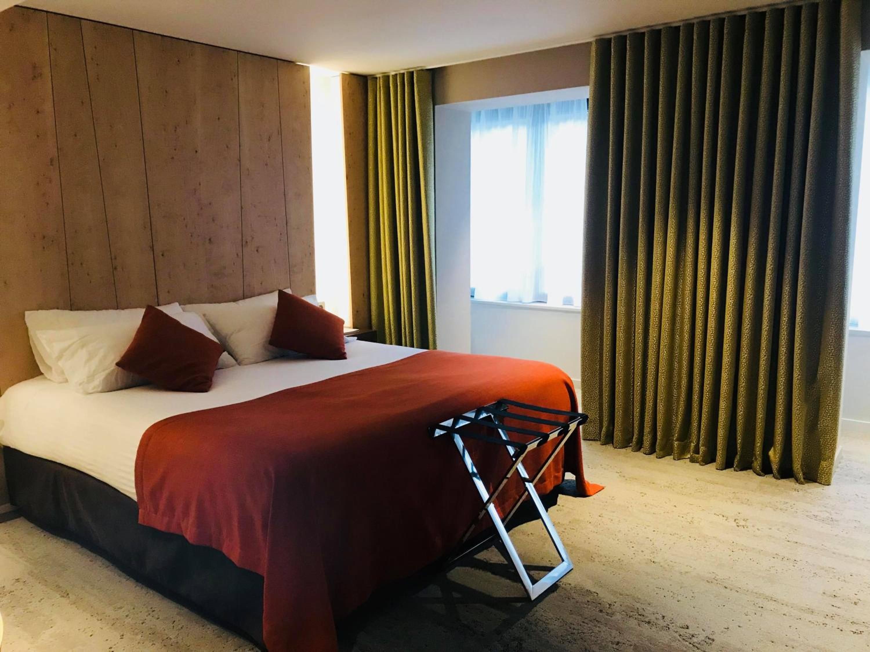 Habitación de hotel con cama, ventana con cortinas y vista al exterior.
