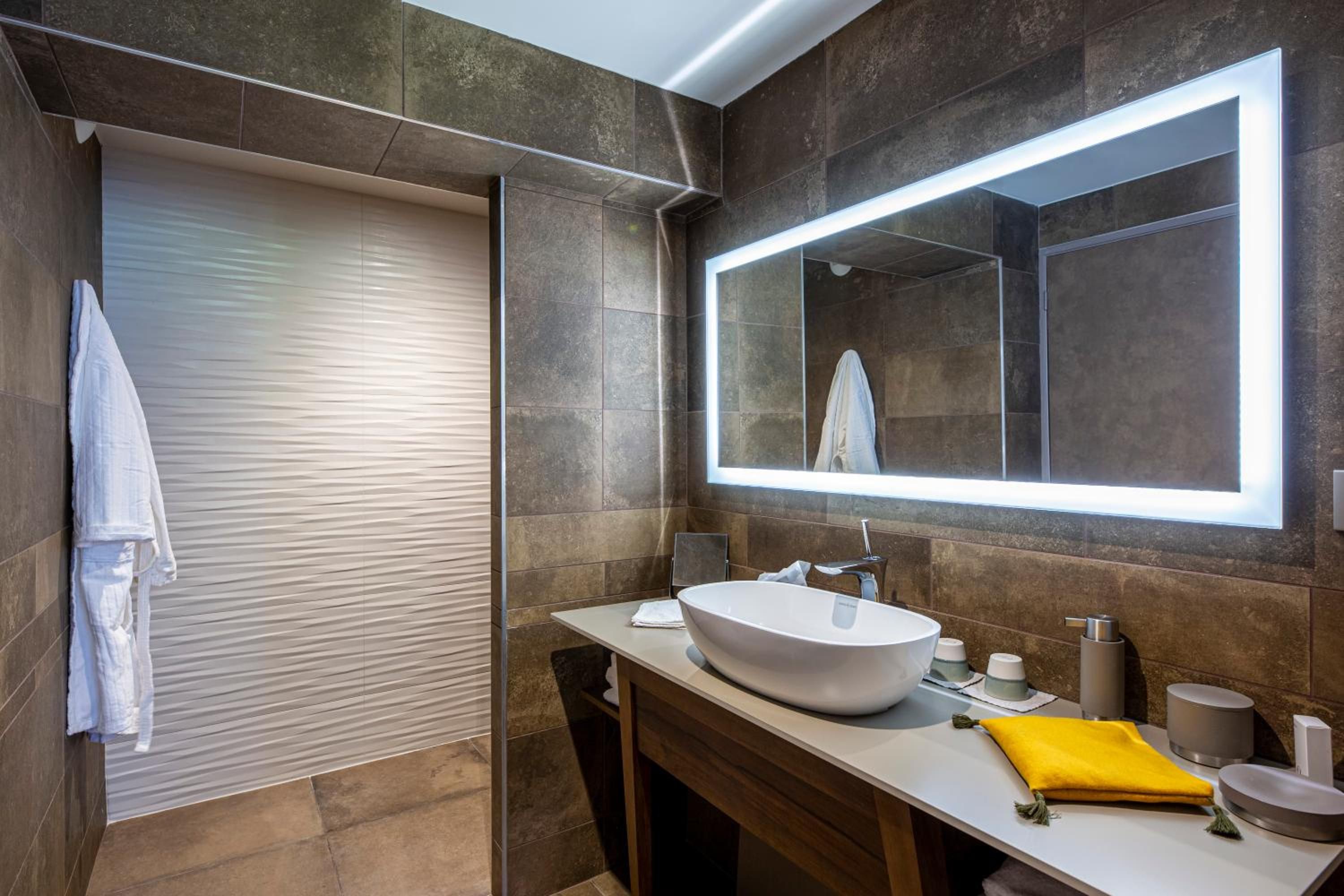 A modern bathroom with a large mirror, a white sink, and a towel rack.