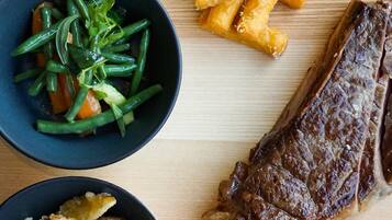 A wooden table with a steak, green beans, and fried items.