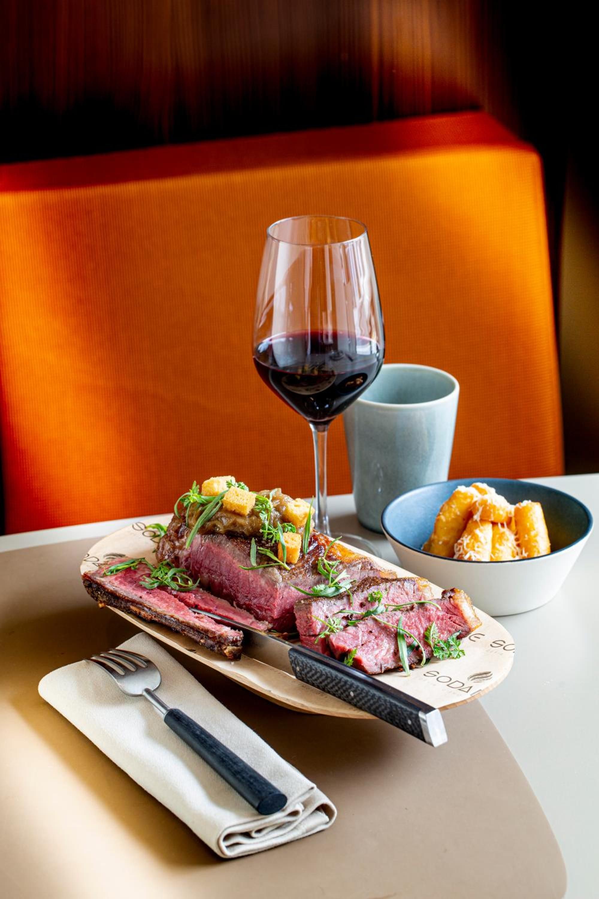 Una mesa de comedor con un plato de comida, una copa de vino y un bol.