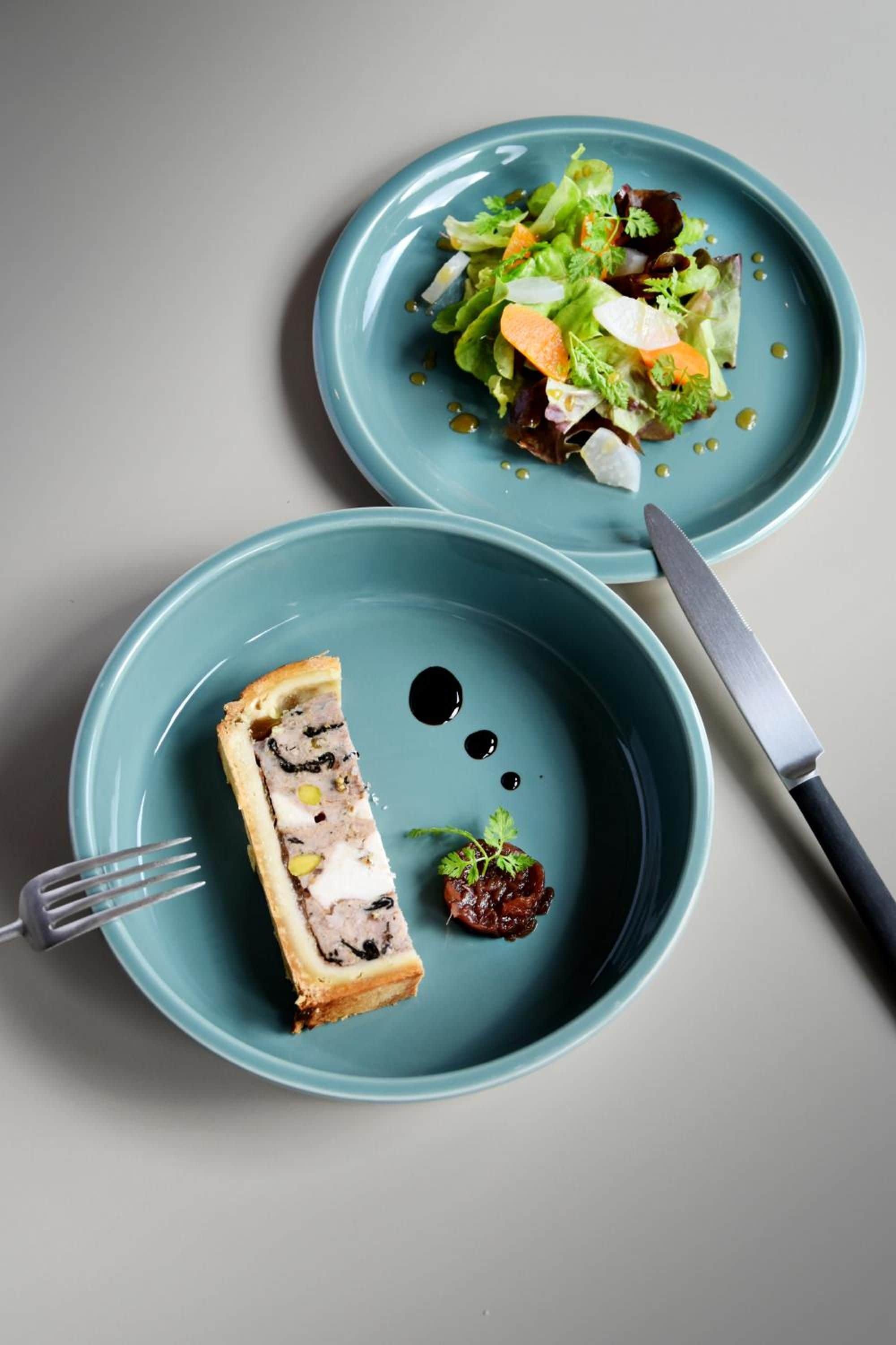 Two plates with food items, a fork, and a knife on a table.