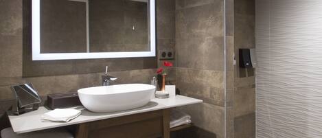 A modern bathroom with a large mirror, a white sink, and a shower area.