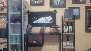 Una habitación acogedora con refrigerador, estantes con botellas, una máquina de café y un muro decorado con obras de arte enmarcadas.