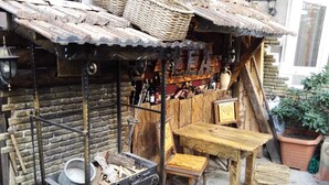 Un espacio de estar al aire libre de estilo rústico, con una mesa y sillas de madera, una parrilla de metal y un muro de ladrillo.