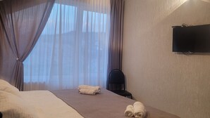 Una habitación de hotel con una cama grande, un televisor de pantalla plana en la pared y una silla.