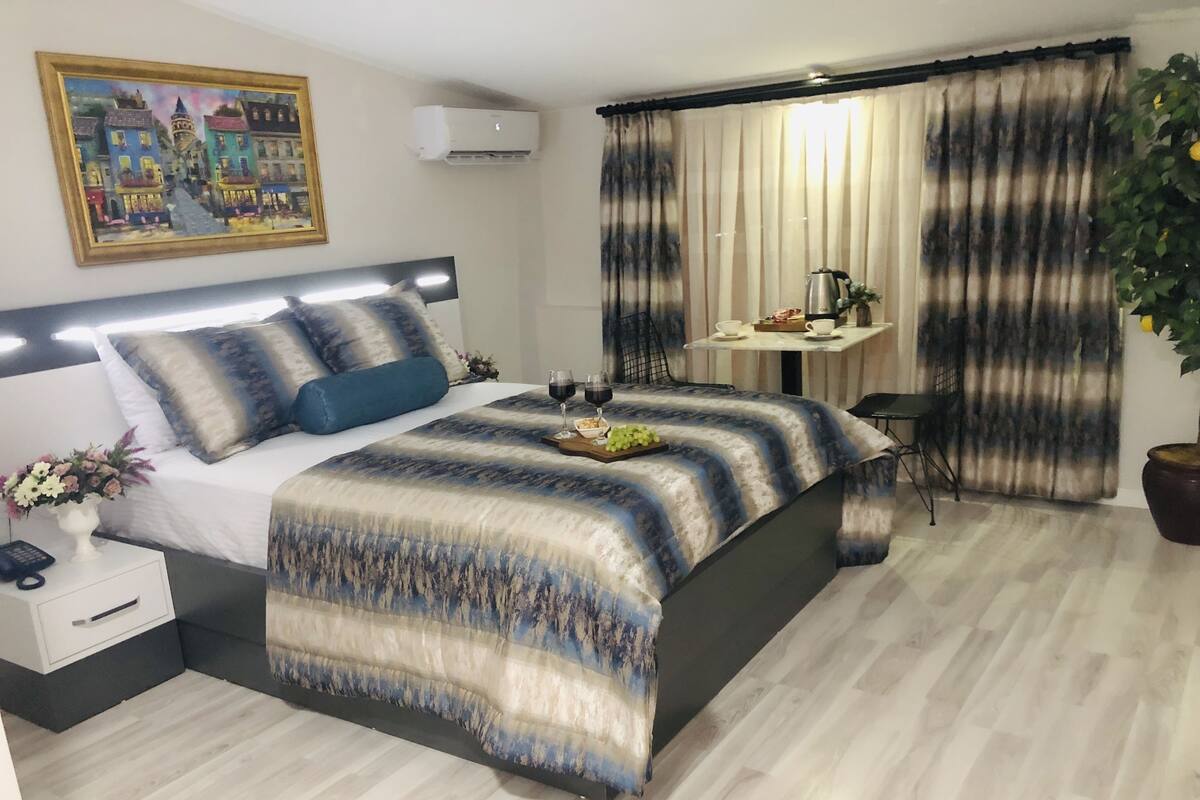 A modern bedroom with a large bed, bedside table, and a small desk with a chair.