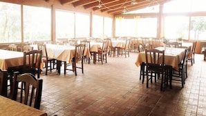 A spacious dining area with multiple tables and chairs, large windows, and a wooden ceiling. - La Magione del Capitano (Montecorvino Pugliano)