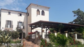 A two-story building with a covered patio area and a small tower-like structure. - La Magione del Capitano (Montecorvino Pugliano)