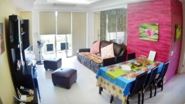 Uma sala de estar ampla com uma mesa de jantar, um sofá e uma grande janela que oferece muita luz natural.