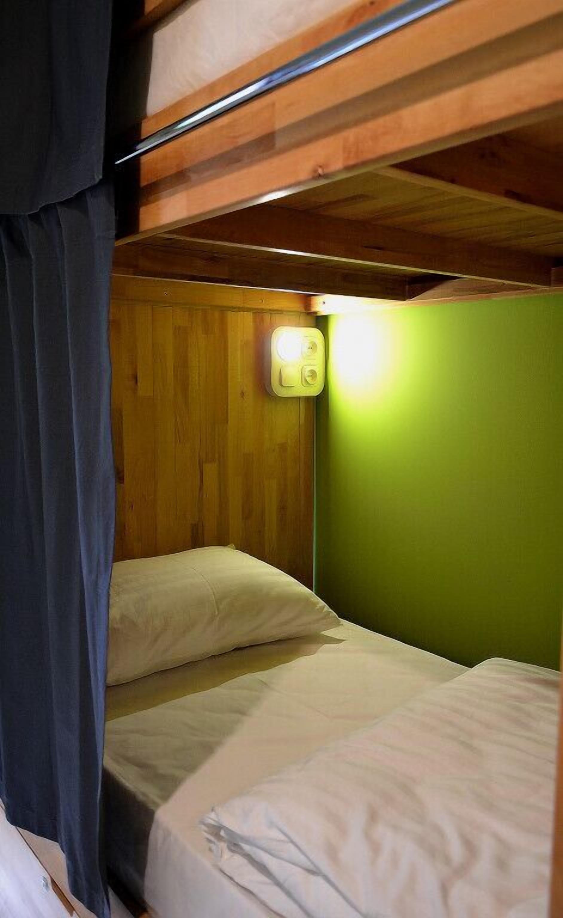 A bunk bed room with wooden walls and a green accent wall.
