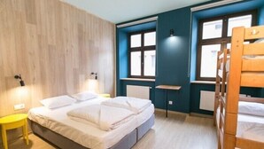 A bedroom with a bed, a wooden bunk bed, a small table, and a window. - Dream Hostel Lviv (Lviv)