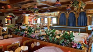 A restaurant with wooden interiors, tables set with white tablecloths, and floral centerpieces. - Hotel Sonnenblick (Staffelstein)