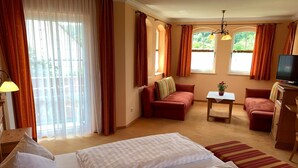 A hotel room with two beds, a sofa, a television, and a small table with a plant. - Hotel Sonnenblick (Staffelstein)