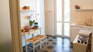 A compact kitchen with a dining table, chairs, a stove, and a sink.