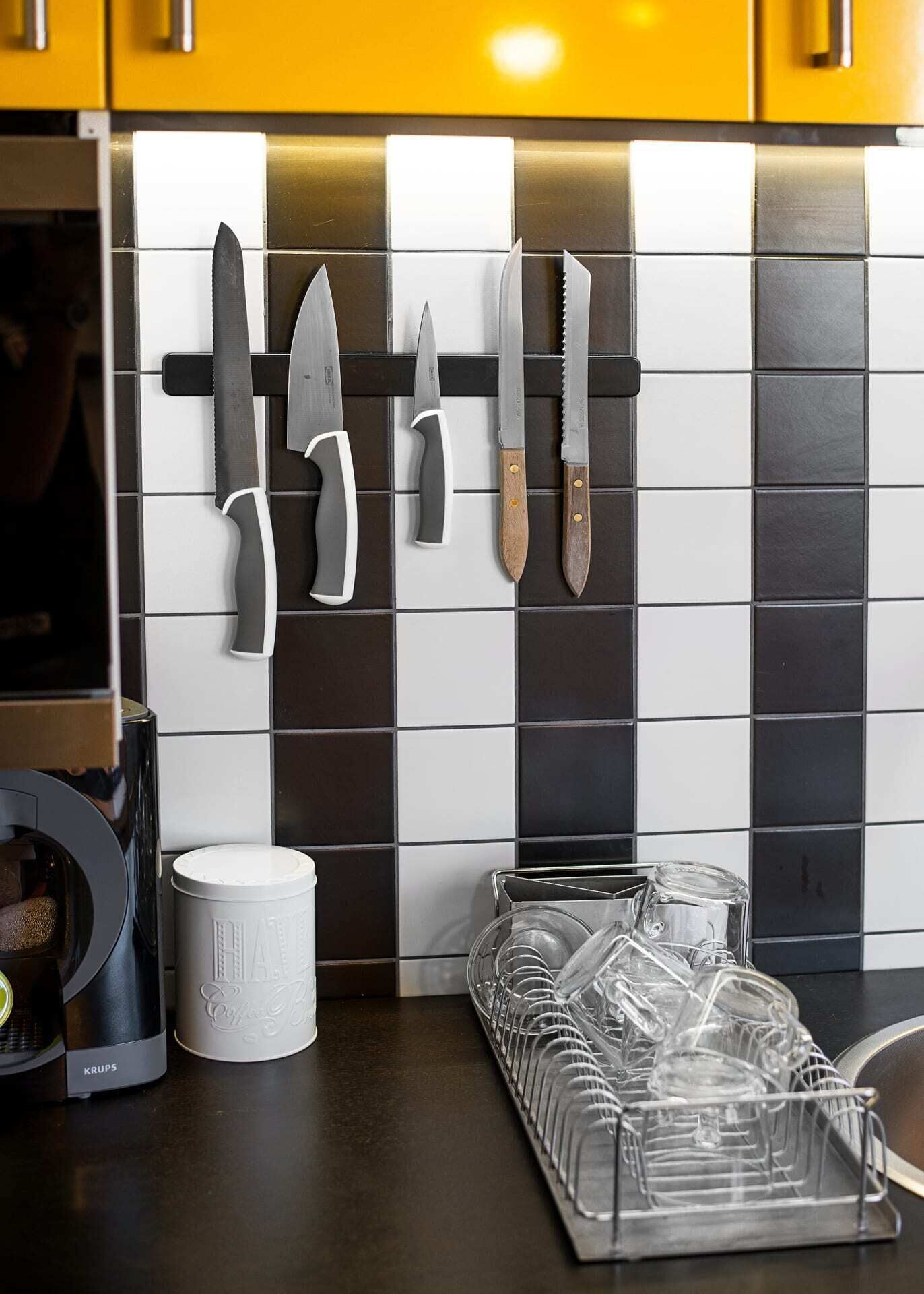 A kitchen with a knife rack, a coffee machine, and a glassware holder.