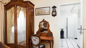 A room with a wooden cabinet, a mirror, a chair, and a tiled floor. - At the Fountain Apartment (Warsaw)