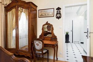 Una habitación con un armario de madera, un espejo, una silla y suelo de baldosas.