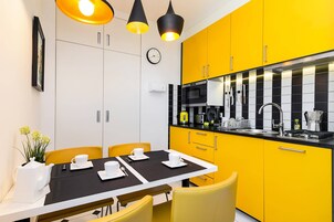 Una cocina moderna con armarios amarillos, una encimera negra y una zona de comedor con una mesa dispuesta para dos.