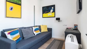 A modern living room with a grey sofa, colorful cushions, a flat-screen TV, and artwork on the walls. - At the Fountain Apartment (Warsaw)