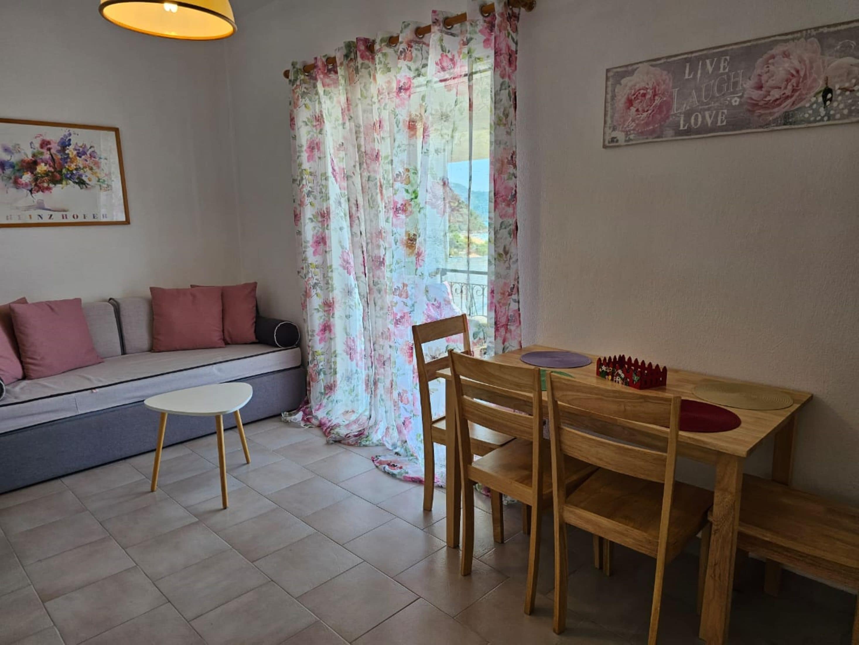 A cozy living room with a sofa, a small round table, and a wooden dining table with chairs.