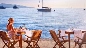 A coastal dining area with tables and chairs, overlooking a calm sea with boats. - La Voile d'Or (Saint-Jean-Cap-Ferrat)