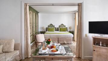 Ein Hotelzimmer mit Bett, Esstisch mit Frühstück, Fernseher und Holzschrank.