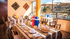 Un espace repas avec des tables préparées pour le petit-déjeuner, offrant une vue sur l’extérieur.