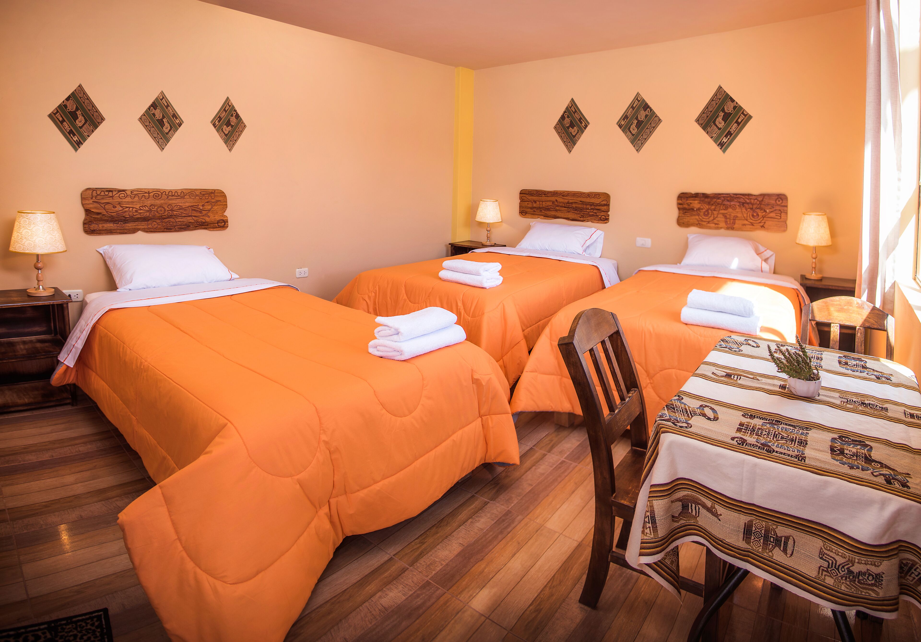 Habitación de hotel con dos camas, cabeceros de madera y una mesa de comedor con mantel.