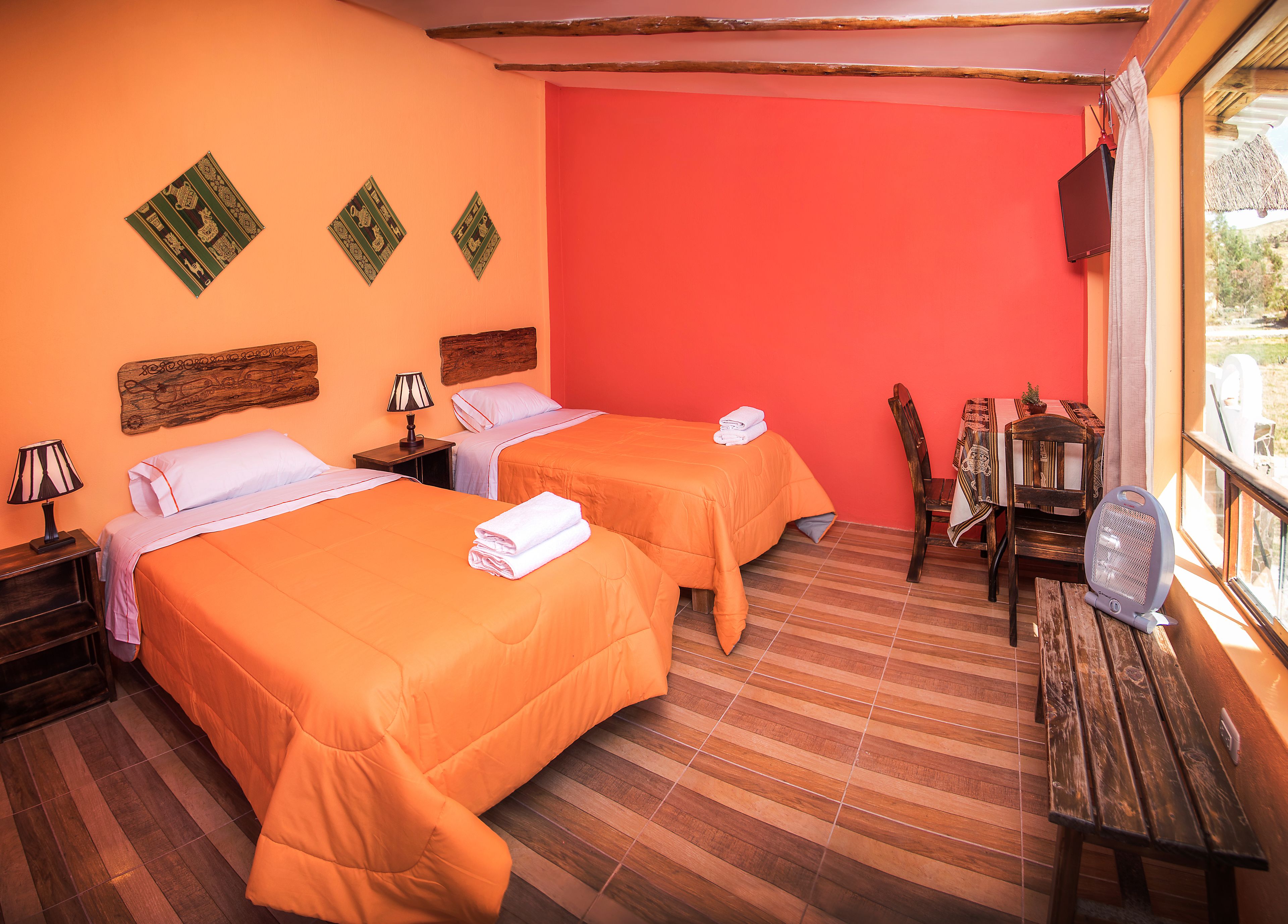 Une chambre d’hôtel avec deux lits, un bureau en bois, une chaise et un téléviseur.