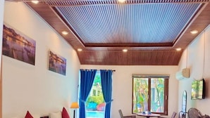 Une chambre d’hôtel avec un grand lit, un bureau avec une chaise, un ventilateur et une vue sur une piscine.