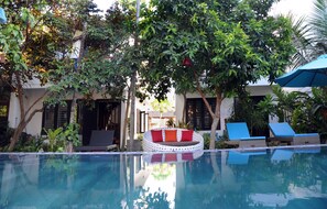 Una piscina al aire libre, sillones reclinables de piscina