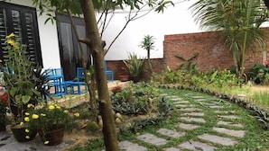 Un jardin avec un chemin de pierres, des plantes en pot et un mur de briques.