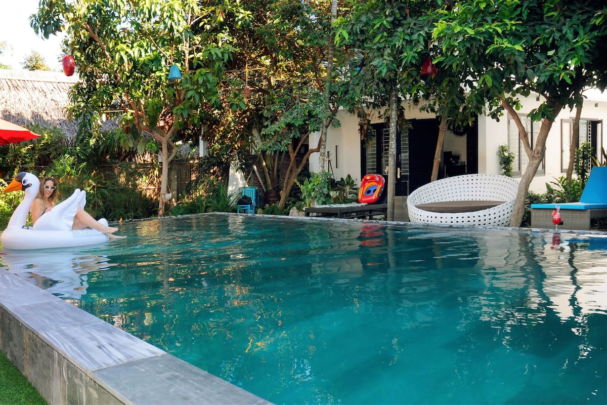 A swimming pool with a swan float and lounge chairs.