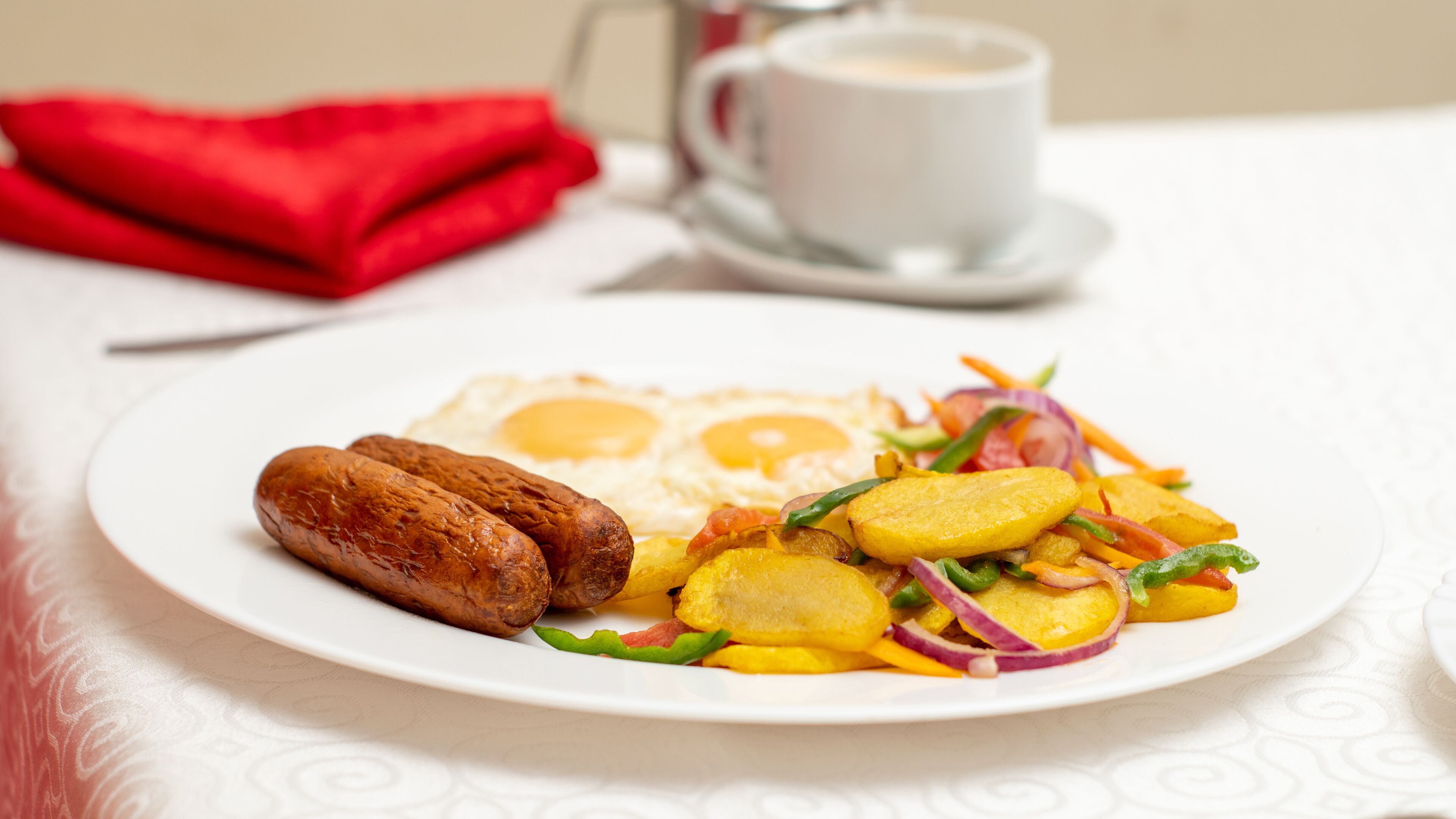 Un plato con salchichas, huevos fritos y una ensalada de verduras.