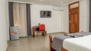 Una habitación de hotel con cama, escritorio con silla, televisor y armario.