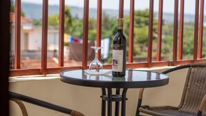 Un balcón con una mesa, una botella de vino y una copa de vino.