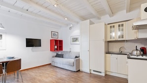 Eine moderne Küche mit weißen Schränken, einem grauen Sofa und einem Esstisch mit Stühlen.