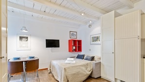 Ein Schlafzimmer mit Bett, Schreibtisch, Stuhl, Fernseher und Kleiderschrank.