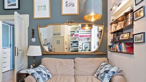 A cozy living room with a beige sofa, a large mirror, and a bookshelf filled with books and framed photos. - Flatty Apartments Garigliano (Milan)