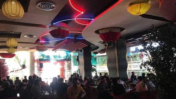 An indoor dining area with multiple tables and chairs, a ceiling with decorative lighting, and a view of the outside through large windows. - Ngoc Se Hotel (Pleiku)